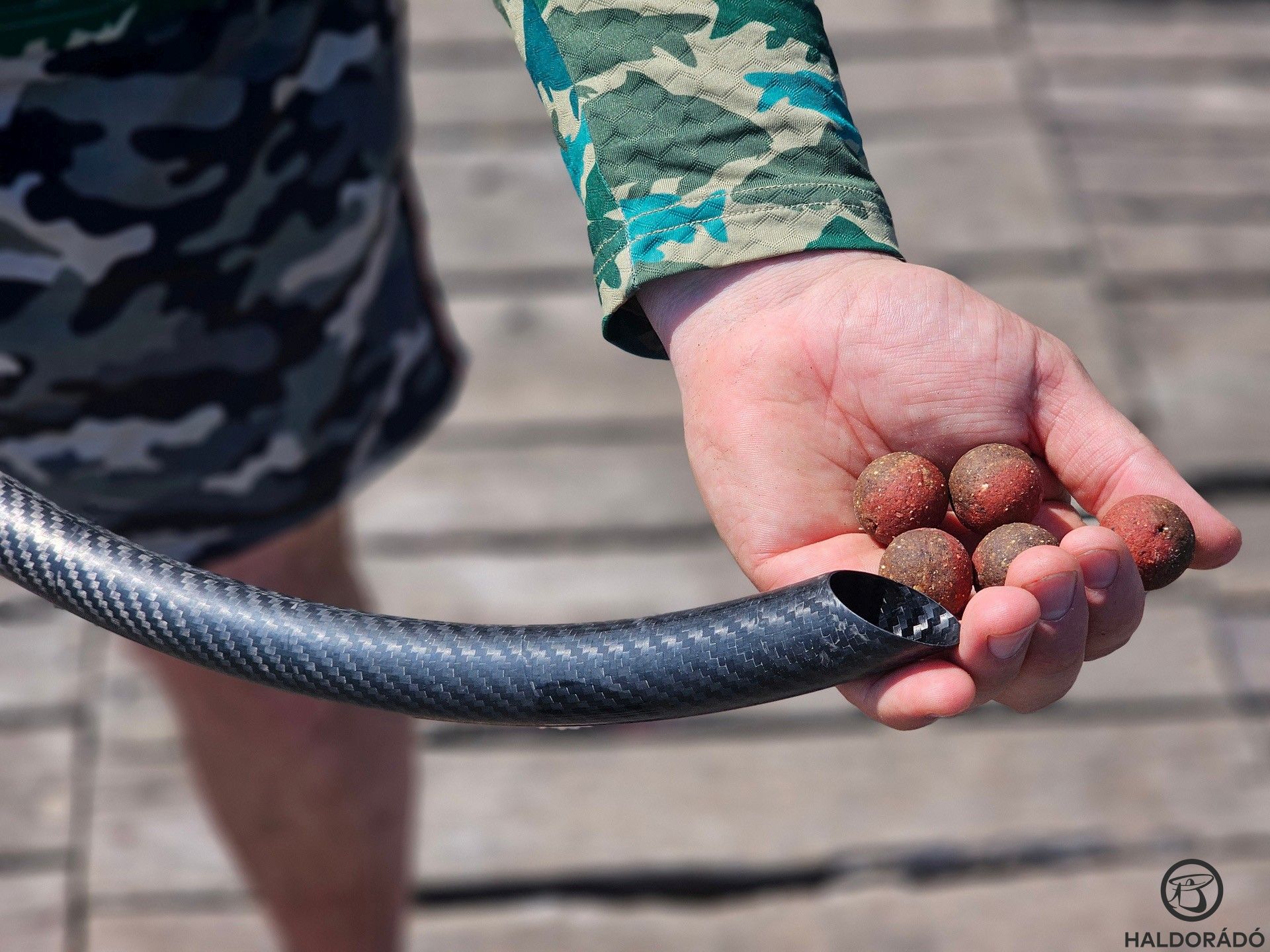 Amikor nem lehetett vízre menni, dobócsővel oldottam meg az etetést. A módszer lépéseit a következő képeken láthatjátok. Először is pár szem bojlit a kezünkbe veszünk…